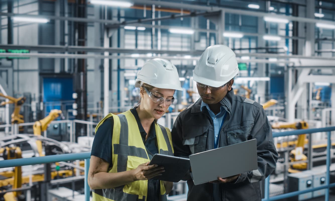 Two engineers reviewing AI insights from a laptop and tablet.