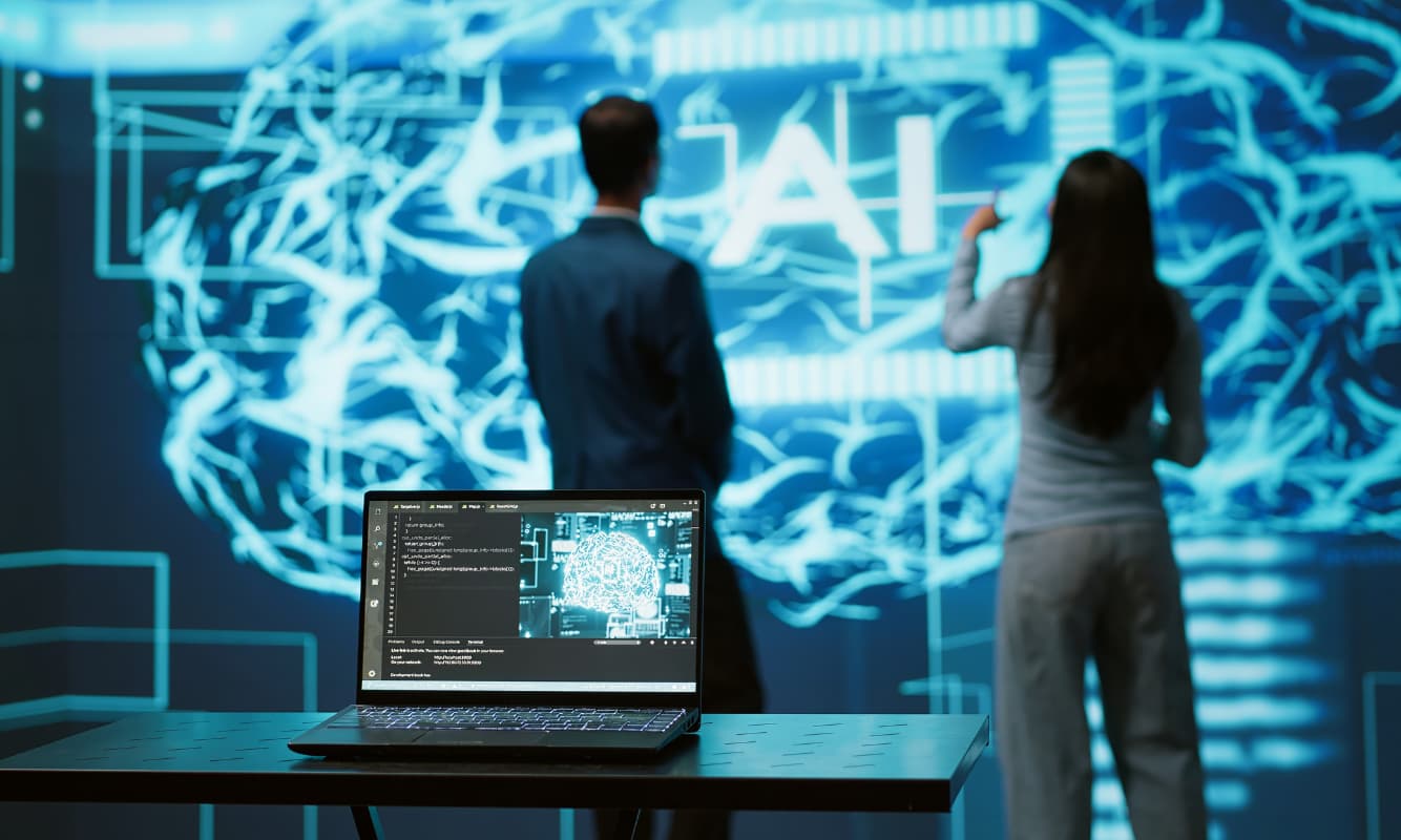 Two engineers facing a large screen with the letters AI