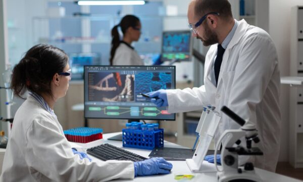 Two clinicians analyzing genomic data on a computer.